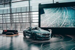 Elegant luxury coupe showcased in a modern Munich auto showroom with glass architecture.