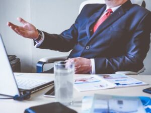 Professional man gesturing in a business meeting at an office desk, conveying confidence and leadership.