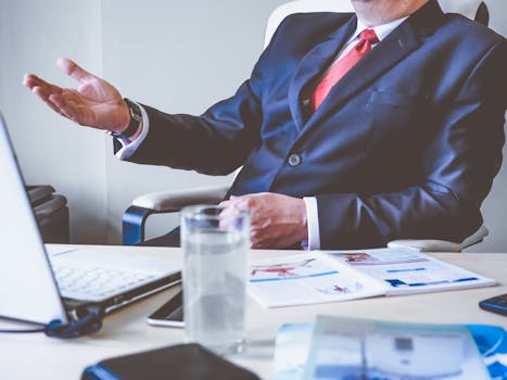 Professional man gesturing in a business meeting at an office desk, conveying confidence and leadership.